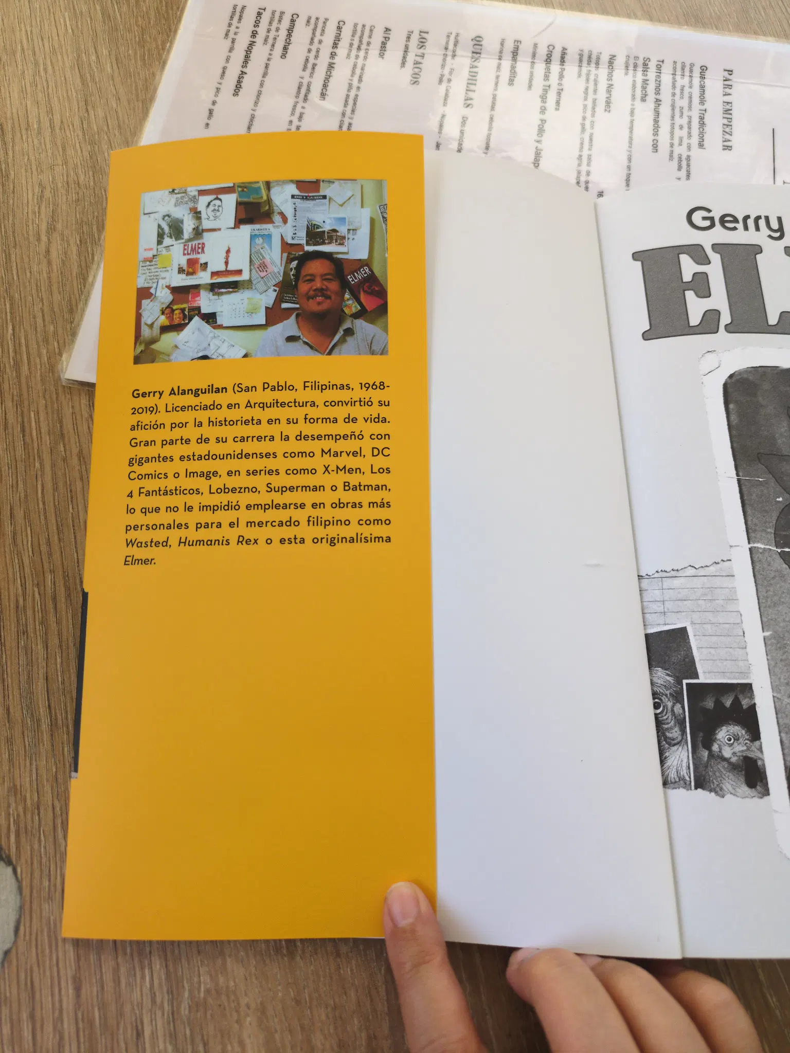 Inside of the book jacket showing a photo of the author. A man poses in front of a corkboard showing his works and personal items